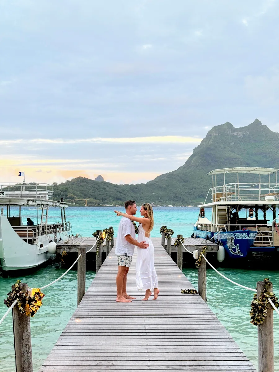 Megs and Pat on a flower-lined dock in Bora Bora at sunset